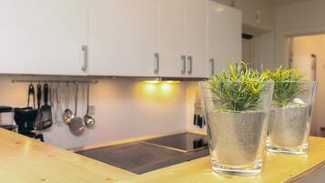 A kitchen with white cabinets, a wooden countertop, and two glass vases with plants.