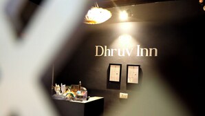 A dark interior with the text 'Dhruv Inn' on the wall, a small desk with various items, and a hanging light fixture. - Hotel Dhruv Inn (Bareilly)