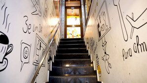 A staircase with hand-drawn illustrations and text on the walls, leading to a brightly lit area. - Hotel Dhruv Inn (Bareilly)