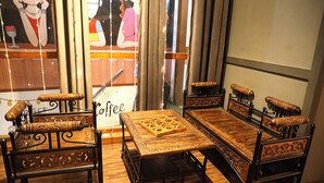 A traditional wooden sofa set with intricate carvings, a matching wooden coffee table, and a decorative chair with a carved backrest. - Hotel Dhruv Inn (Bareilly)