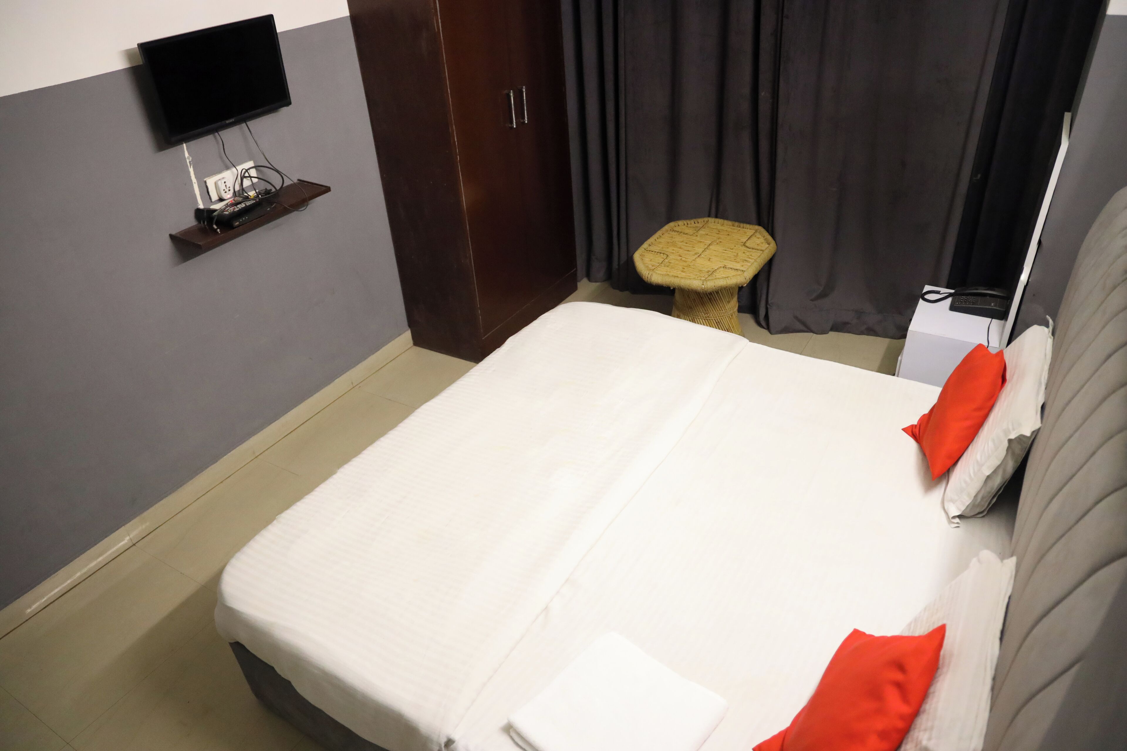 Una camera d'albergo con un letto, una televisione a muro, un piccolo tavolo e un armadio.