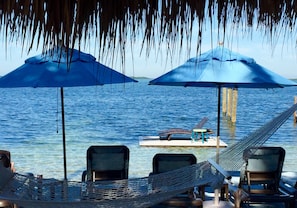 A beachside lounge with two blue umbrellas, a hammock, and lounge chairs. - Seafarer Key Largo (Key Largo)