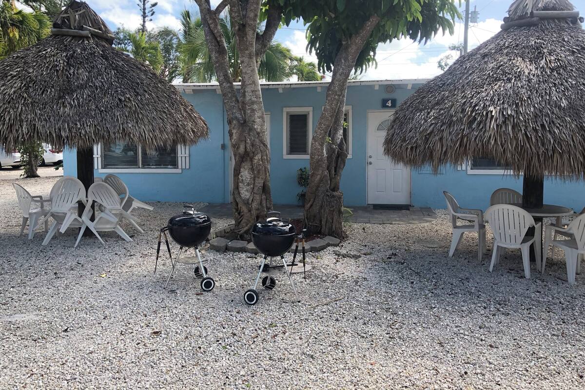 A building with a blue exterior, two thatched umbrellas, and a seating area with plastic chairs.