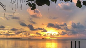 A sunset over a calm body of water with a dock and lounge chairs. - Seafarer Key Largo (Key Largo)