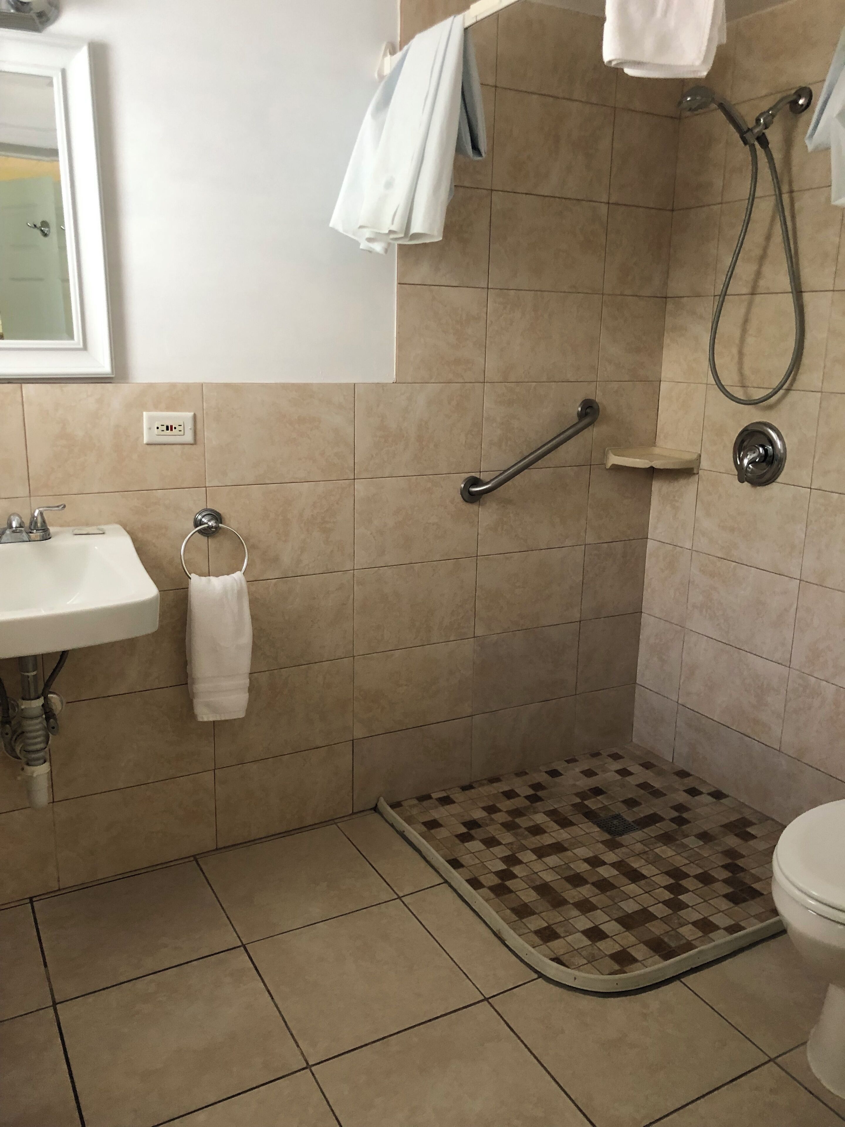 Un baño con lavamanos, inodoro, ducha y un felpudo de cuadros.
