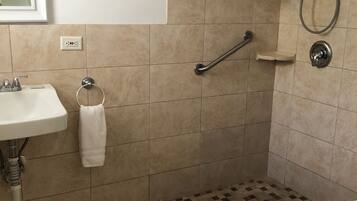 Un baño con lavamanos, inodoro, ducha y un felpudo de cuadros.