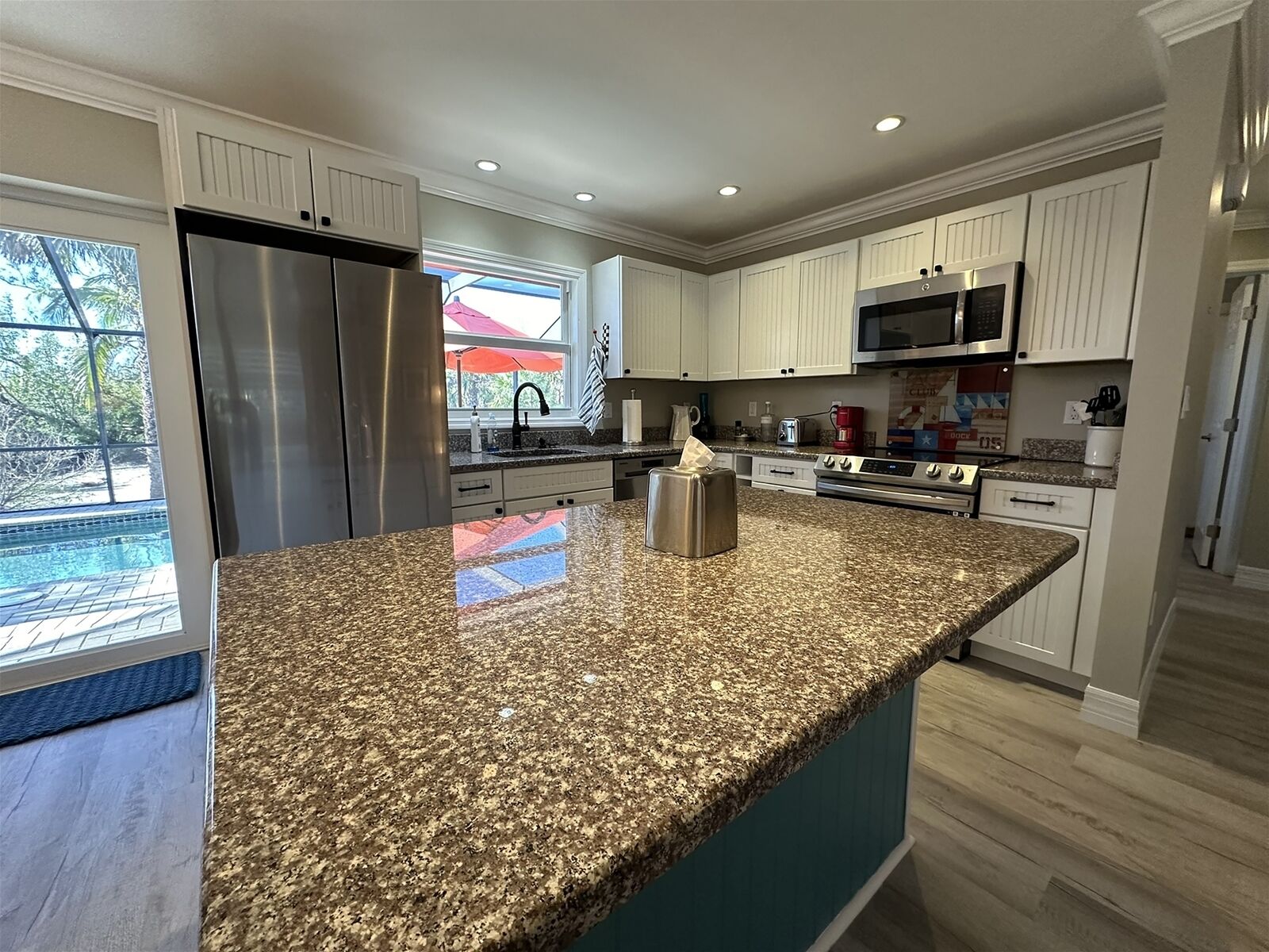 A modern kitchen with granite countertops, stainless steel appliances, and a large island.