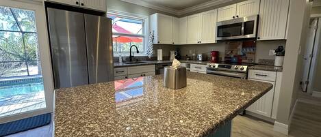 A modern kitchen with granite countertops, stainless steel appliances, and a large island.