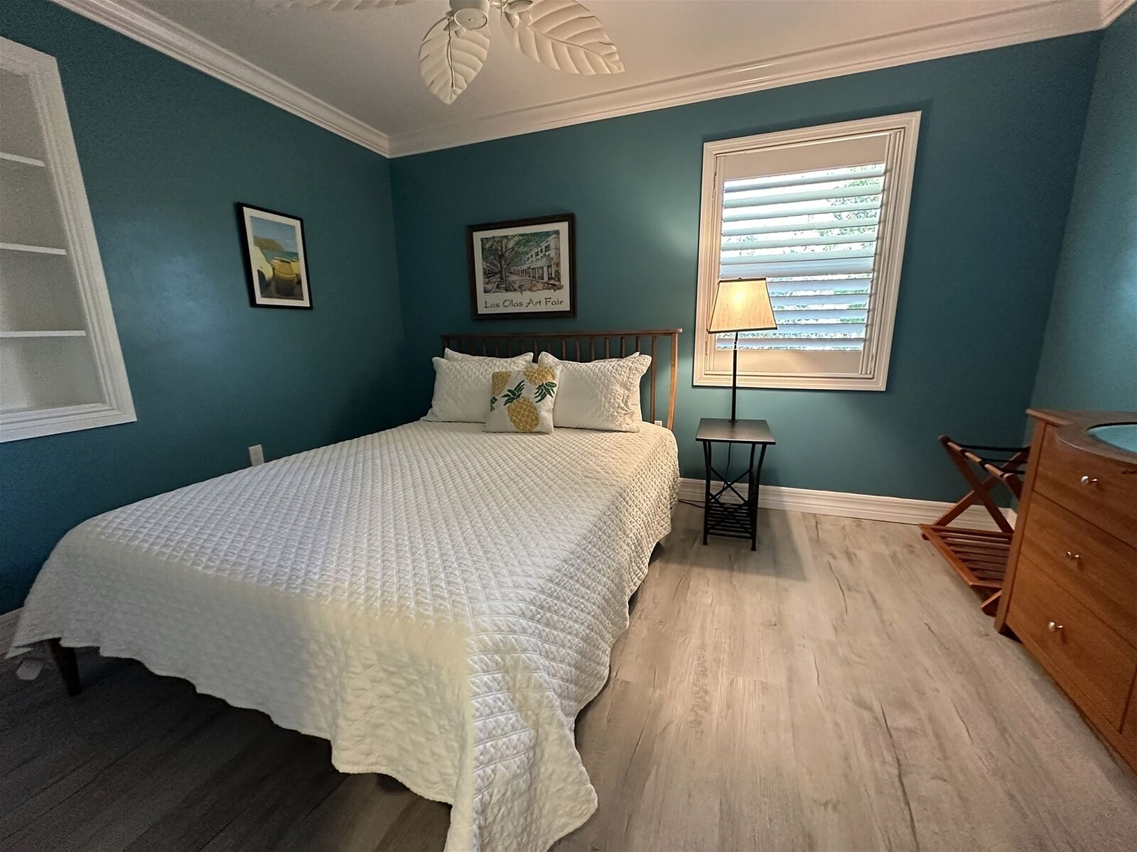A bedroom with a bed, a nightstand, a lamp, and a dresser.