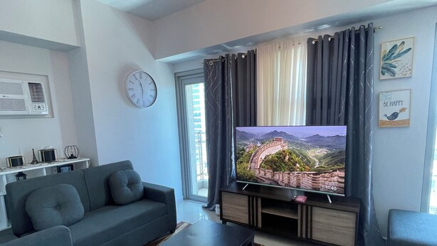 Ein modernes Wohnzimmer mit einer Sofagarnitur, einem Couchtisch, einem Flachbildfernseher und einer dekorativen Leuchte.