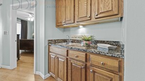 Una cocina con armarios de madera, encimeras de granito y un lavaplatos de acero inoxidable.