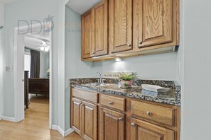 Una cocina con armarios de madera, encimeras de granito y un lavaplatos de acero inoxidable.