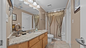 A bathroom with a double sink vanity, a toilet, and a shower curtain. - Legacy Tower II 609 | Stunning Coastal Views! (Gulfport)