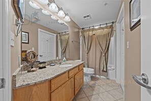 A bathroom with a double sink vanity, a toilet, and a shower curtain. - Legacy Tower II 609 | Stunning Coastal Views! (Gulfport)