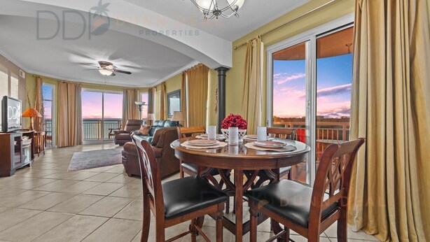 A spacious living room with a dining area, large windows, and a balcony with a view. - Legacy Tower II 609 | Stunning Coastal Views! (Gulfport)