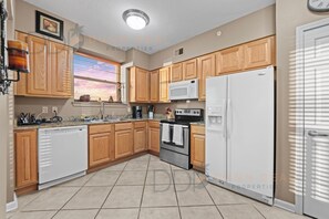 A kitchen with wooden cabinets, a white refrigerator, a microwave, a stove, and a dishwasher. - Legacy Tower II 609 | Stunning Coastal Views! (Gulfport)