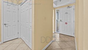 A hallway with beige walls and white doors, including a door with a 'no entry' sign. - Legacy Tower II 907 | Deluxe Unit with Stunning Coastal Views! (Gulfport)