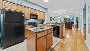 Una cocina moderna con armarios de madera, un refrigerador negro y encimeras de granito.