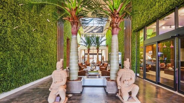 A lobby with green walls, two stone statues, a central seating area, and a glass entrance. - DLuxx Magic Jacuzzi Home 3 miles from Disney 7454 (Kissimmee)