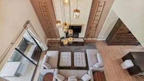 A modern living room with a sofa set, a fireplace, and hanging pendant lights. - DLuxx Magic Jacuzzi Home 3 miles from Disney 7454 (Kissimmee)