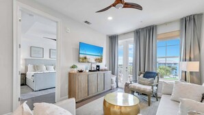 A modern living room with a sofa, a coffee table, a side table, a chair, a cabinet, and a ceiling fan. - ☀️Short Walk to Beach-Pools-30A-Gulf Place Residences 203 (Santa Rosa Beach)
