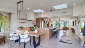 A modern kitchen with a central island, pendant lighting, and a dining area with a large table and chairs. - Partial Ocean Views/Walk to All/Great Location! (La Jolla)