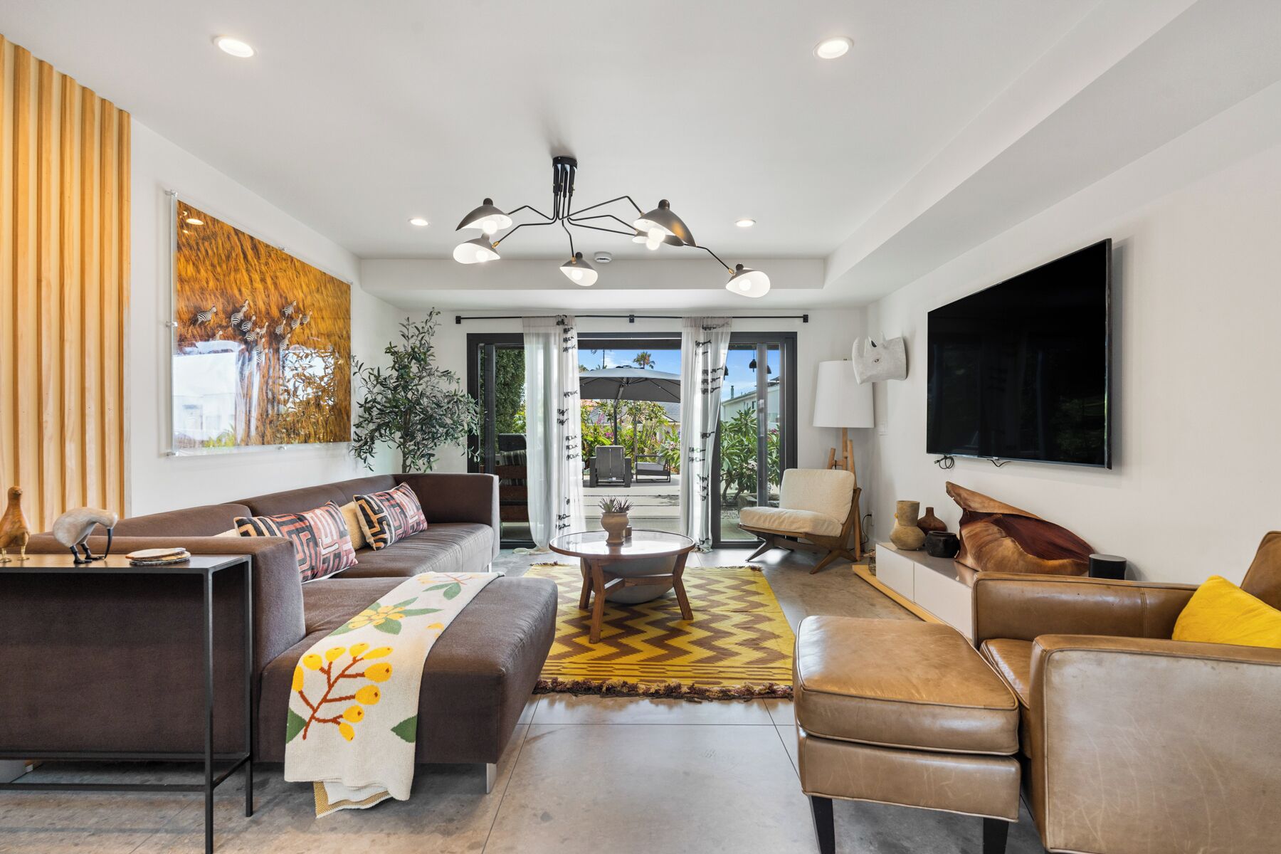 A modern living room with a sofa, armchairs, a coffee table, and a TV.
