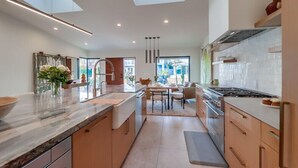 A modern kitchen with a large island, a dining area, and a view of the outdoors. - Partial Ocean Views/Walk to All/Great Location! (La Jolla)