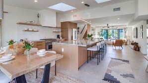A spacious kitchen with a central island, a dining area, and a staircase leading to an upper level. - Partial Ocean Views/Walk to All/Great Location! (La Jolla)
