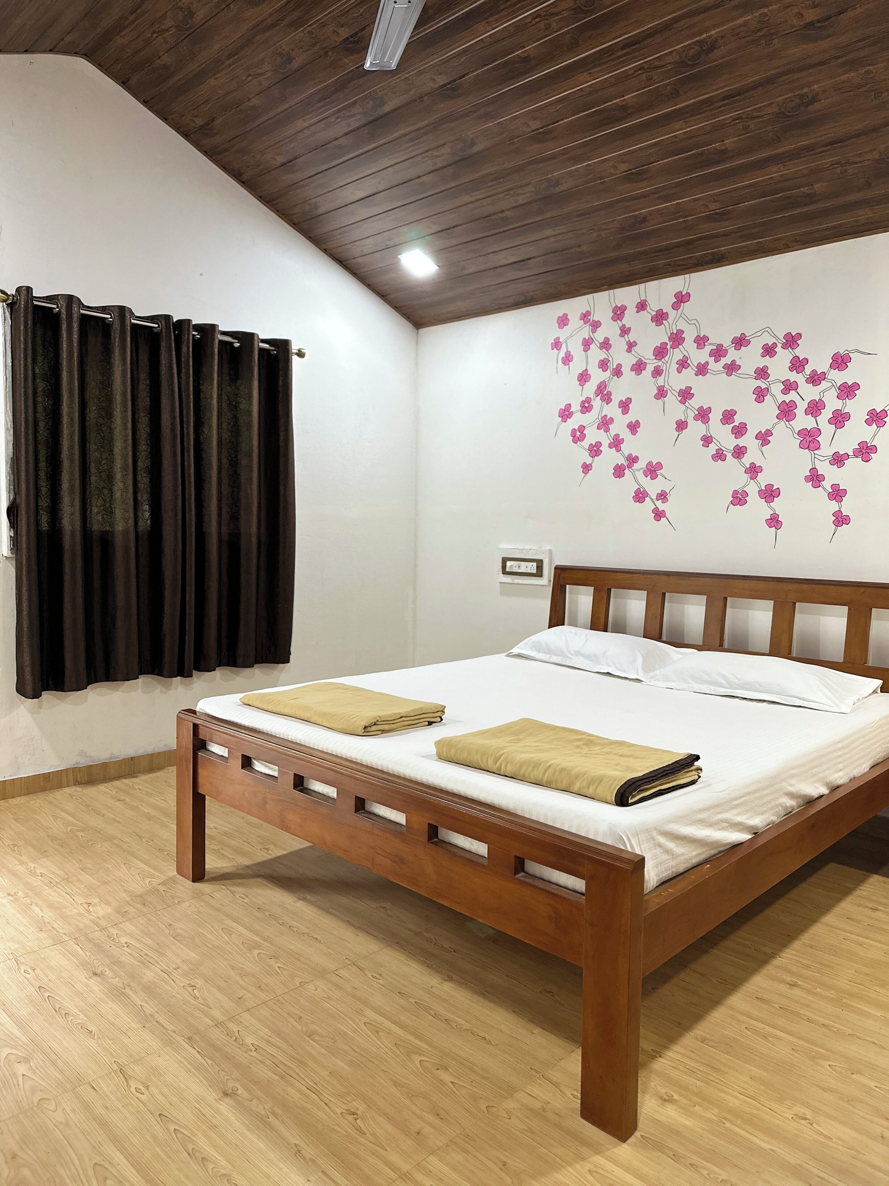 Un dormitorio con cama de madera, paredes blancas, techo de madera y un equipo de aire acondicionado instalado en la pared.