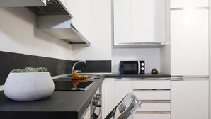 Una cocina moderna con armarios blancos, encimera negra, horno empotrado y microondas.