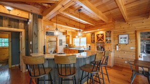L’intérieur d’un chalet en bois comprend une cuisine, un coin bar et un espace repas.