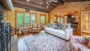 L’intérieur d’une cabane en rondins, avec un canapé blanc, un tapis à motifs et un plafond en bois.