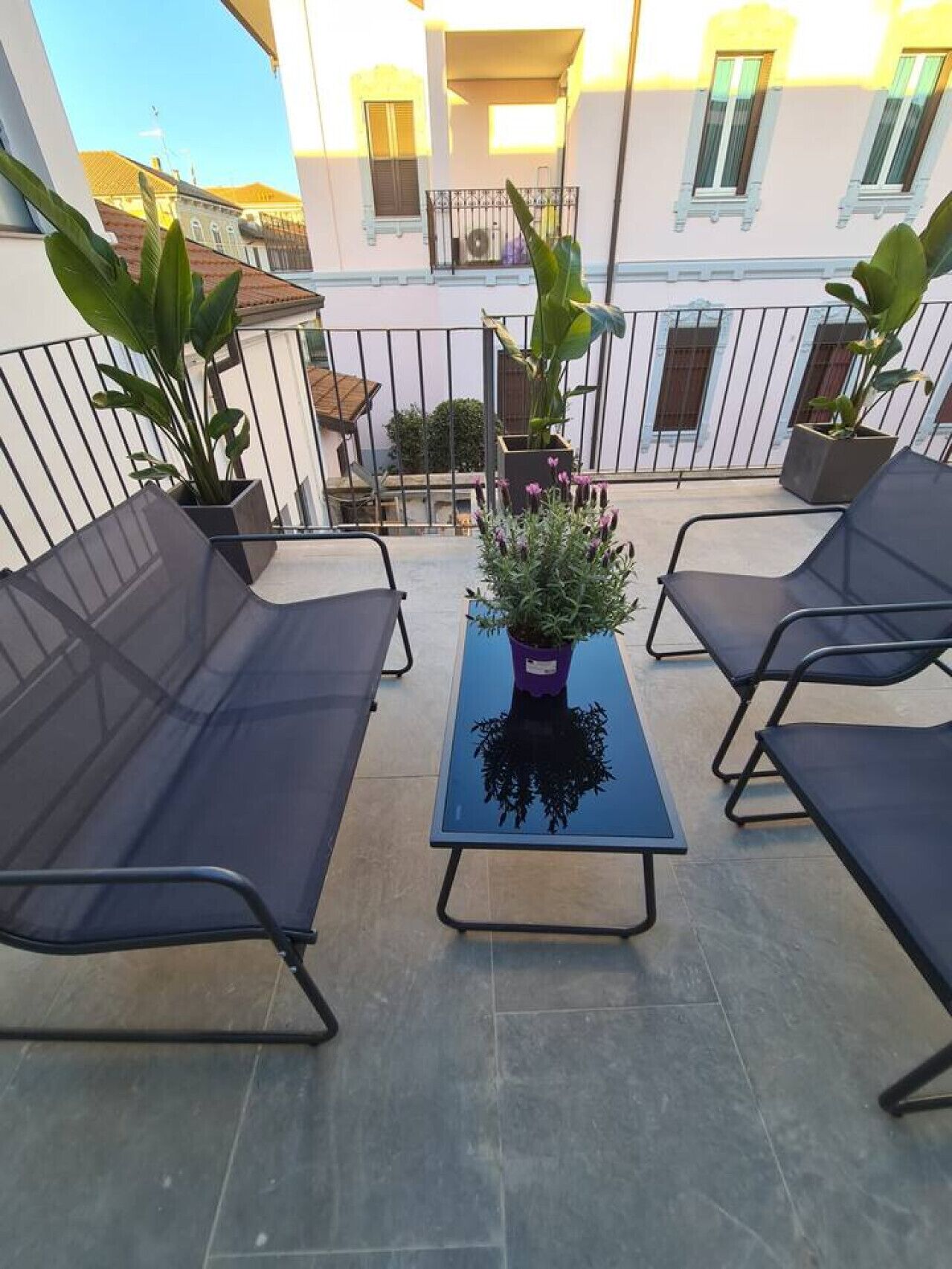 Un balcone con quattro poltrone prendisole, un tavolino e piante in vaso.