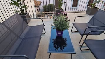 Un balcone con quattro poltrone prendisole, un tavolino e piante in vaso.