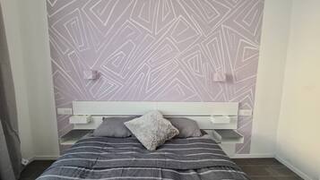 Ein Schlafzimmer mit einem Bett, einem Kopfteil mit Einbauregalen und einer Wand mit Muster.