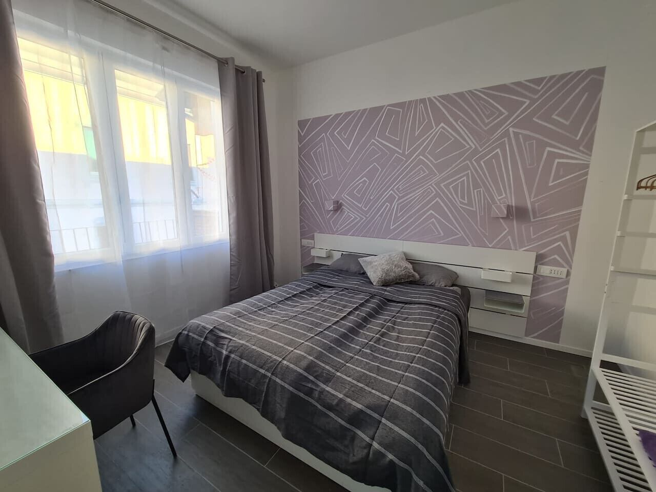 Una camera da letto con un letto, una sedia, un armadio e una parete decorata.