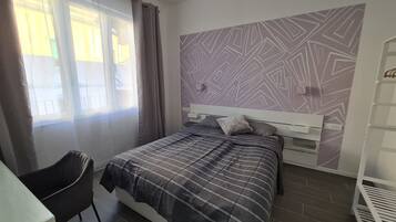 Una camera da letto con un letto, una sedia, un armadio e una parete decorata.