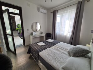 Une chambre d’hôtel avec un lit, un bureau, un miroir et une fenêtre avec des rideaux.