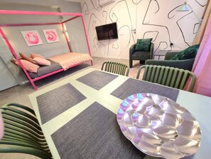 Une chambre moderne avec un lit à baldaquin rose, un téléviseur à écran plat et des œuvres d’art abstraites accrochées aux murs.