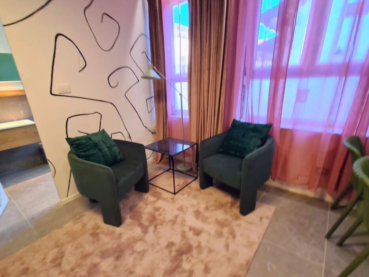 Ein modernes Wohnzimmer mit zwei dunklen Sesseln, einem kleinen Couchtisch und einer großen abstrakten Wanddekoration.