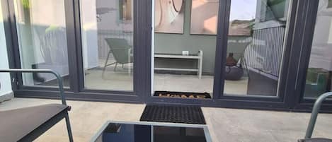 A modern room with a glass partition, a small table with a shell decoration, and a view of the outside balcony area.