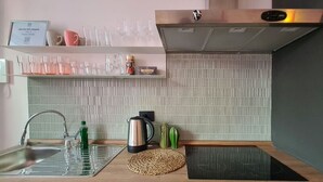 Eine moderne Küche mit Spülbecken aus Edelstahl, einem Wasserkocher und einem integrierten Herd.