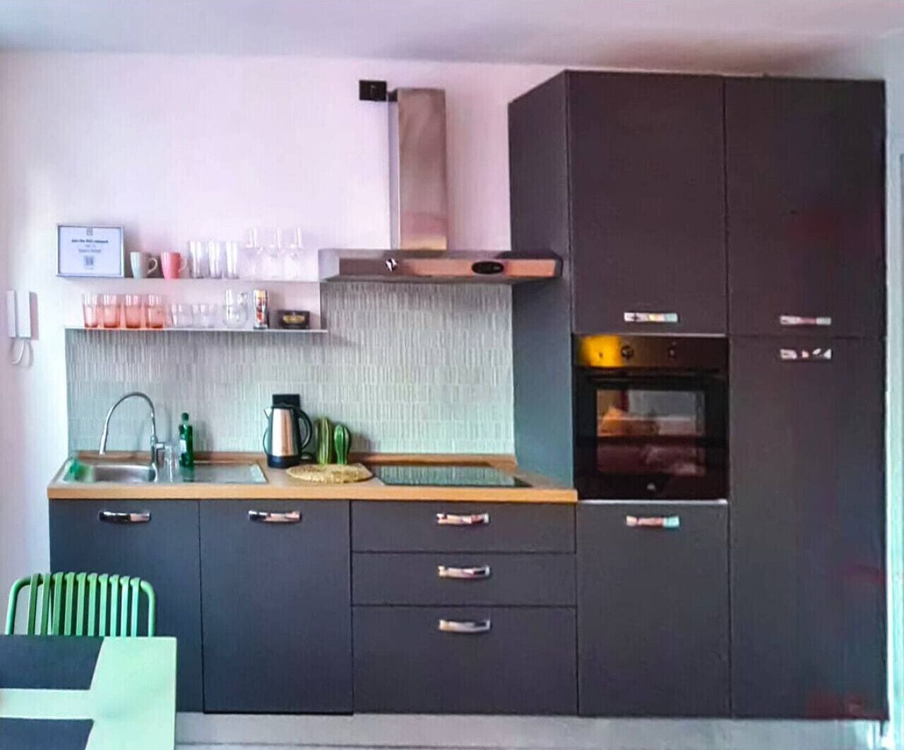 A modern kitchen with dark cabinets, a stainless steel sink, and a built-in oven.