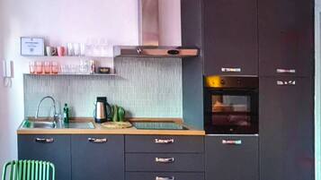 A modern kitchen with dark cabinets, a stainless steel sink, and a built-in oven.