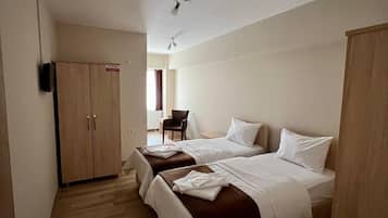 Une chambre d’hôtel avec deux lits, une armoire, un bureau et une chaise.