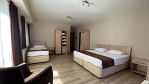 A hotel room with two beds, a wardrobe, a desk, and a chair.