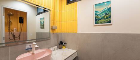 Un baño con un lavamanos rosa, azulejos amarillos, una ventana y un cuadro en la pared.