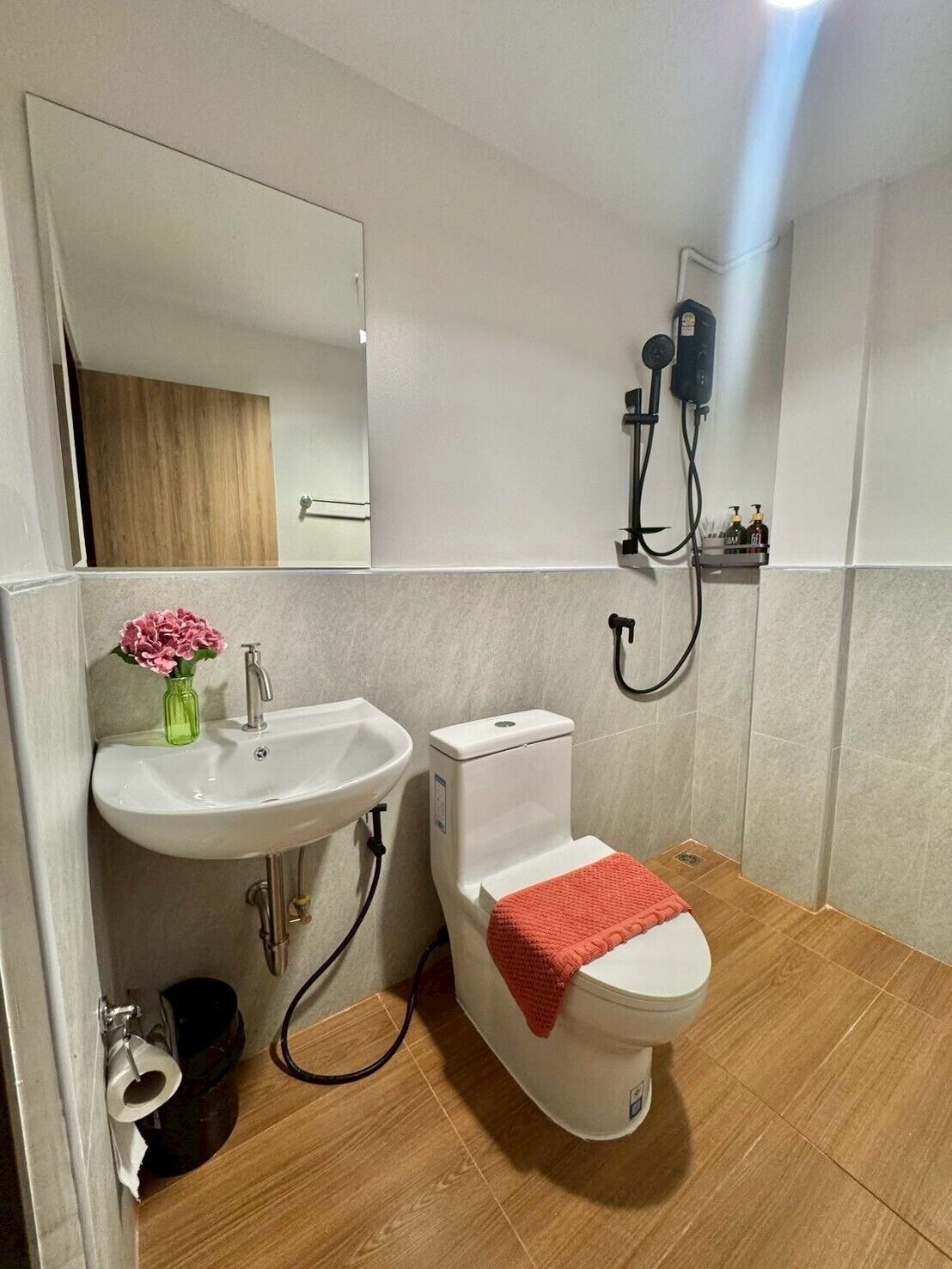 Casa de banho com lavatório branco, sanita e chuveiro.