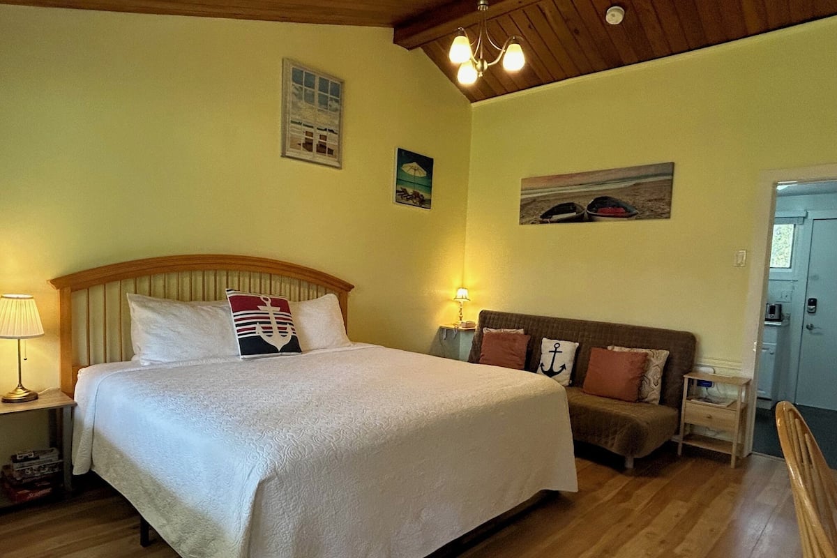 Une chambre à coucher avec un lit, une table de chevet, une lampe, un canapé et une porte.